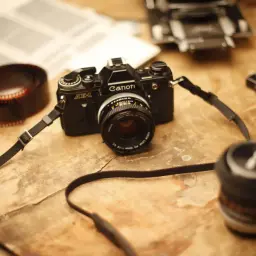 Stary aparat Canon AE-1, rolka kliszy i książki - idealne do blogu fotograficznego.