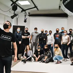 Grupa uczestników kursu fotografii pozuje do wspólnego zdjęcia w studiu.