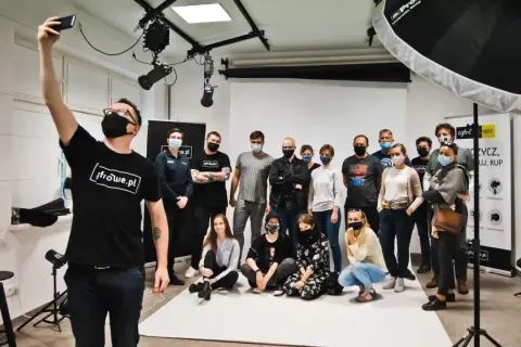 Grupa uczestników kursu fotografii pozuje do wspólnego zdjęcia w studiu.
