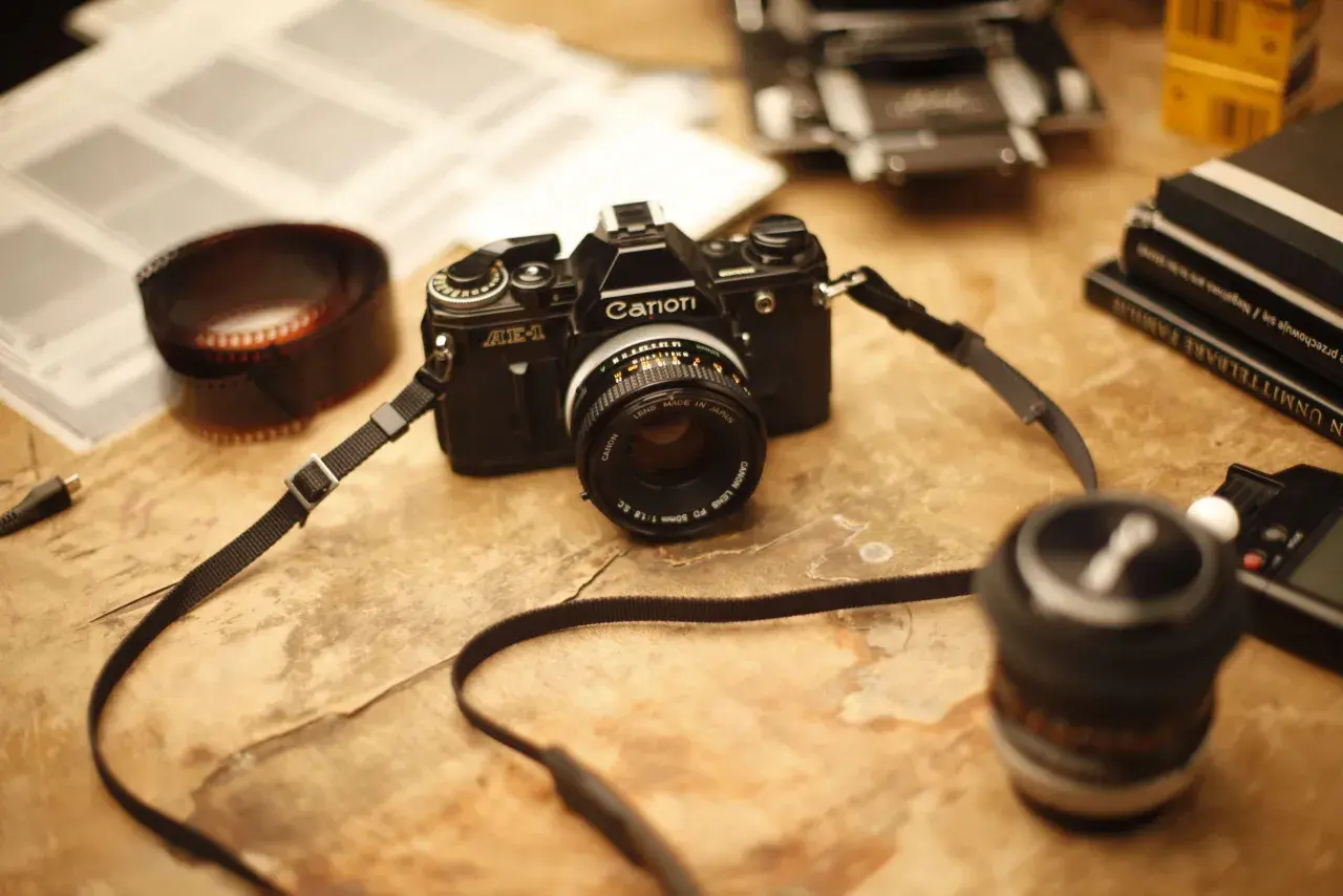 Stary aparat Canon AE-1, rolka kliszy i książki - idealne do blogu fotograficznego.