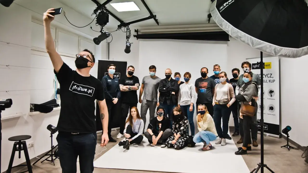 Grupa uczestników kursu fotografii pozuje do wspólnego zdjęcia w studiu.